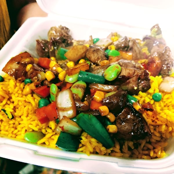 Senegalese beef and vegetable stir-fry with yellow rice in a white takeout container.