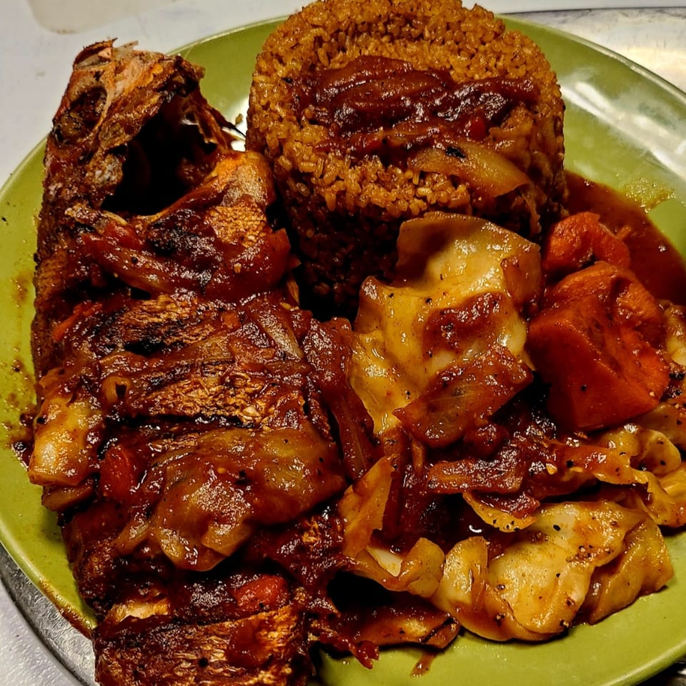 Senegalese Thieboudienne with whole fried fish, rice, and vegetables in a rich sauce.
