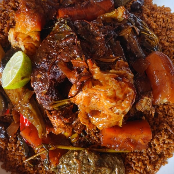 Close-up of Badou Senegalese Cuisine's Thieboudienne, with fish, vegetables, and rice, garnished with lime.
