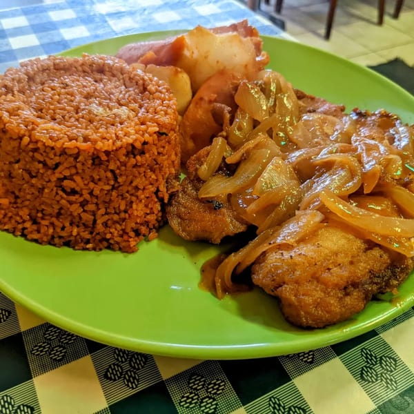 Senegalese Thieboudienne with rice, fish, and caramelized onions on a green plate.